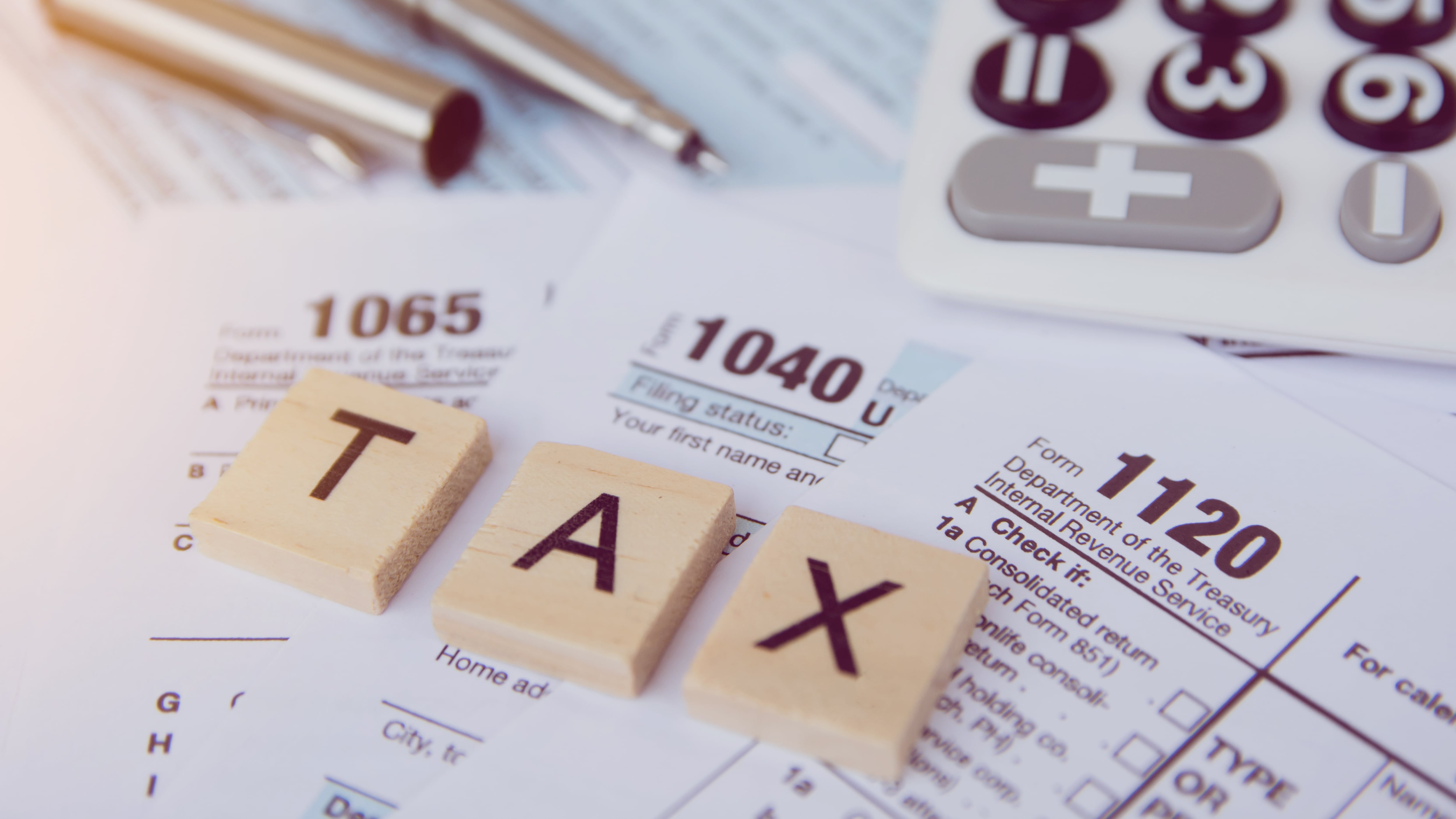 Tax season with wooden alphabet blocks, calculator, pen on 1040 tax form background